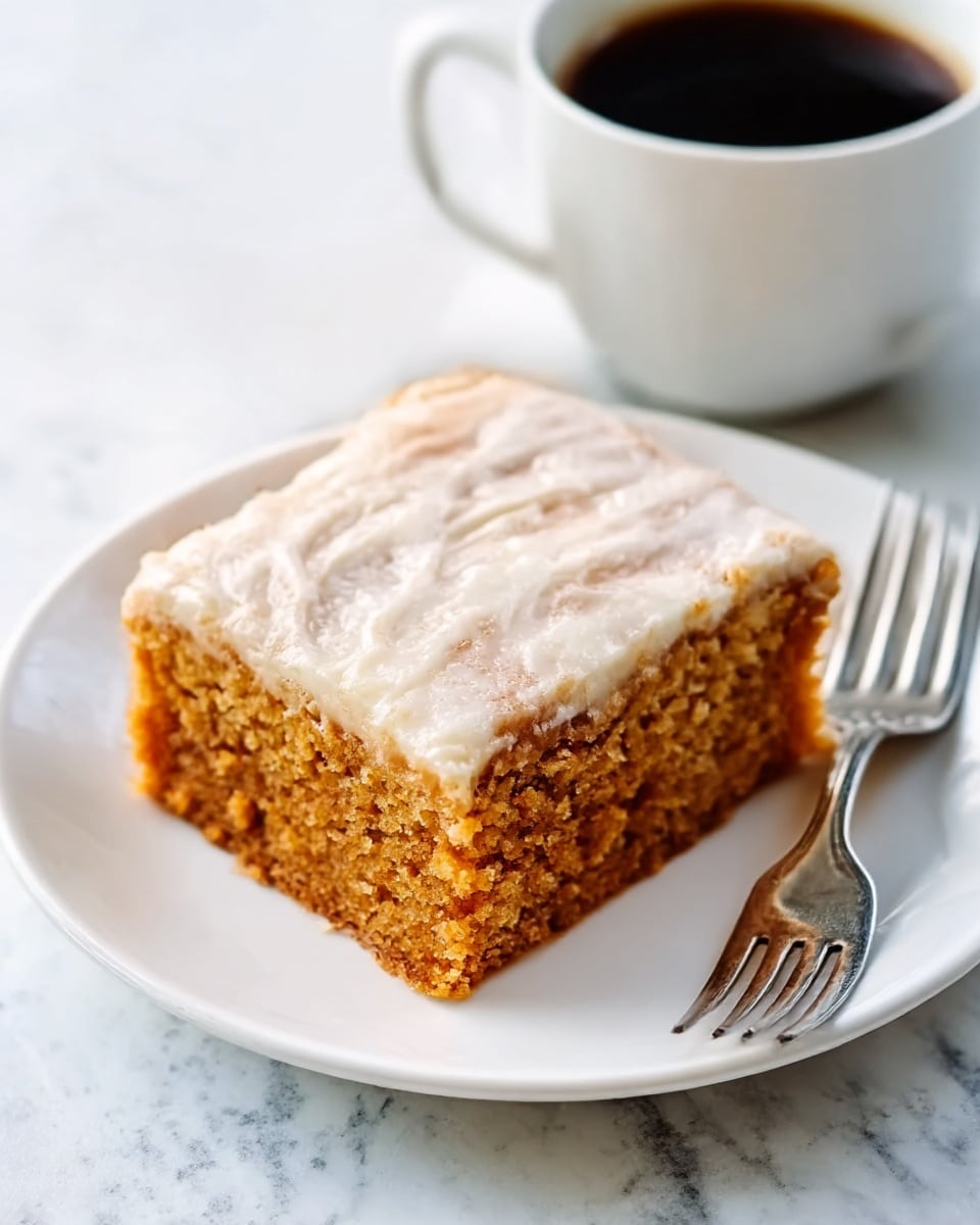 A square piece of cake with two layers is placed on a white scalloped plate; the bottom layer is a moist, light brown cake, and the top layer is a thick, shiny, light-colored frosting with a slightly cracked texture. The cake looks soft and dense, and there is a silver fork to the right of the plate. The background is a white marbled texture with a white cup of dark coffee blurry in the top right corner. photo taken with an iphone --ar 4:5 --v 7