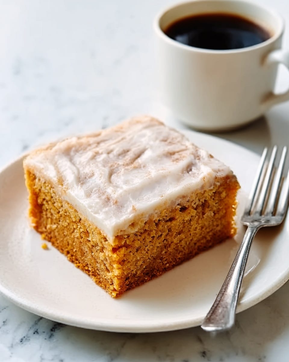 A square piece of two-layer cake sits on a white plate. The bottom layer is a dense, orange-brown cake with a slightly rough texture. The top layer is a lighter, creamy layer with a smooth, glossy white frosting that looks soft and slightly cracked on top. The plate rests on a white marbled surface, and next to the plate is a cup of black coffee in a white cup with a handle. A silver fork is placed to the right of the cake. Photo taken with an iphone --ar 4:5 --v 7