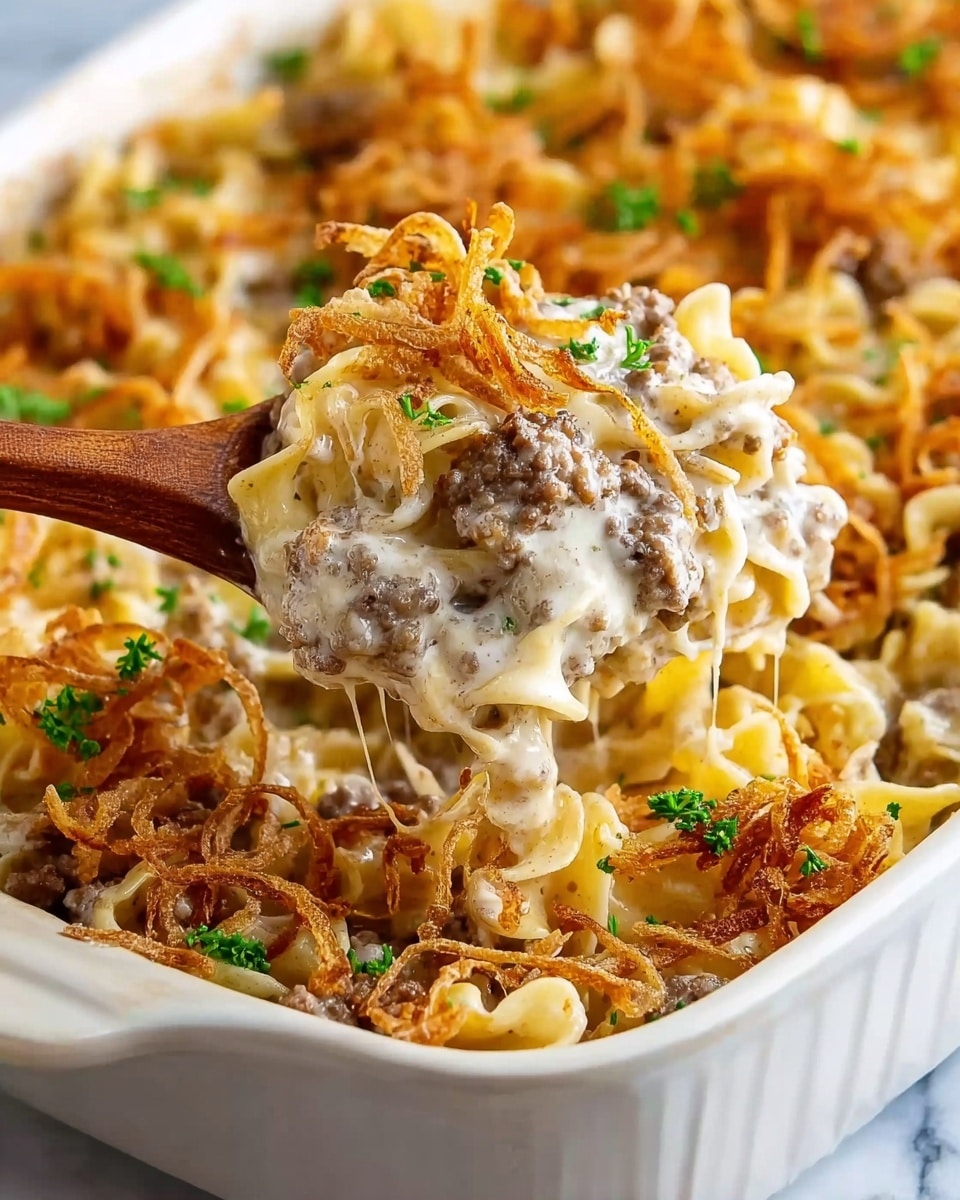 A close-up of a white ceramic baking dish filled with a creamy noodle casserole. The bottom layer is light golden noodles mixed with browned ground meat, covered by a thick, creamy, pale sauce. On top, there is a layer of crispy, thin, light brown fried onions scattered with small green parsley bits. A woman's hand holding a wooden spoon lifts a scoop of the casserole, showing the creamy texture mixed with meat, noodles, and crispy onions. The background is a white marbled texture. Photo taken with an iphone --ar 4:5 --v 7