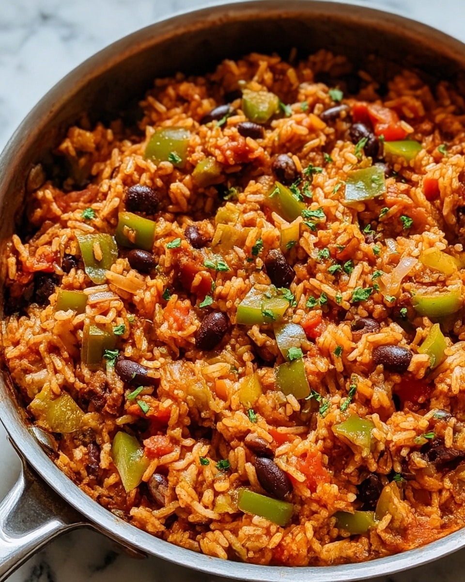 A close-up view of a pan filled with cooked Mexican rice showing one main layer. The rice is orange-red with a moist texture, mixed with pieces of green bell pepper, black beans, diced red tomatoes, and finely chopped cilantro scattered on top. The pan is silver with a black interior, sitting on a white marbled surface. Photo taken with an iphone --ar 4:5 --v 7
