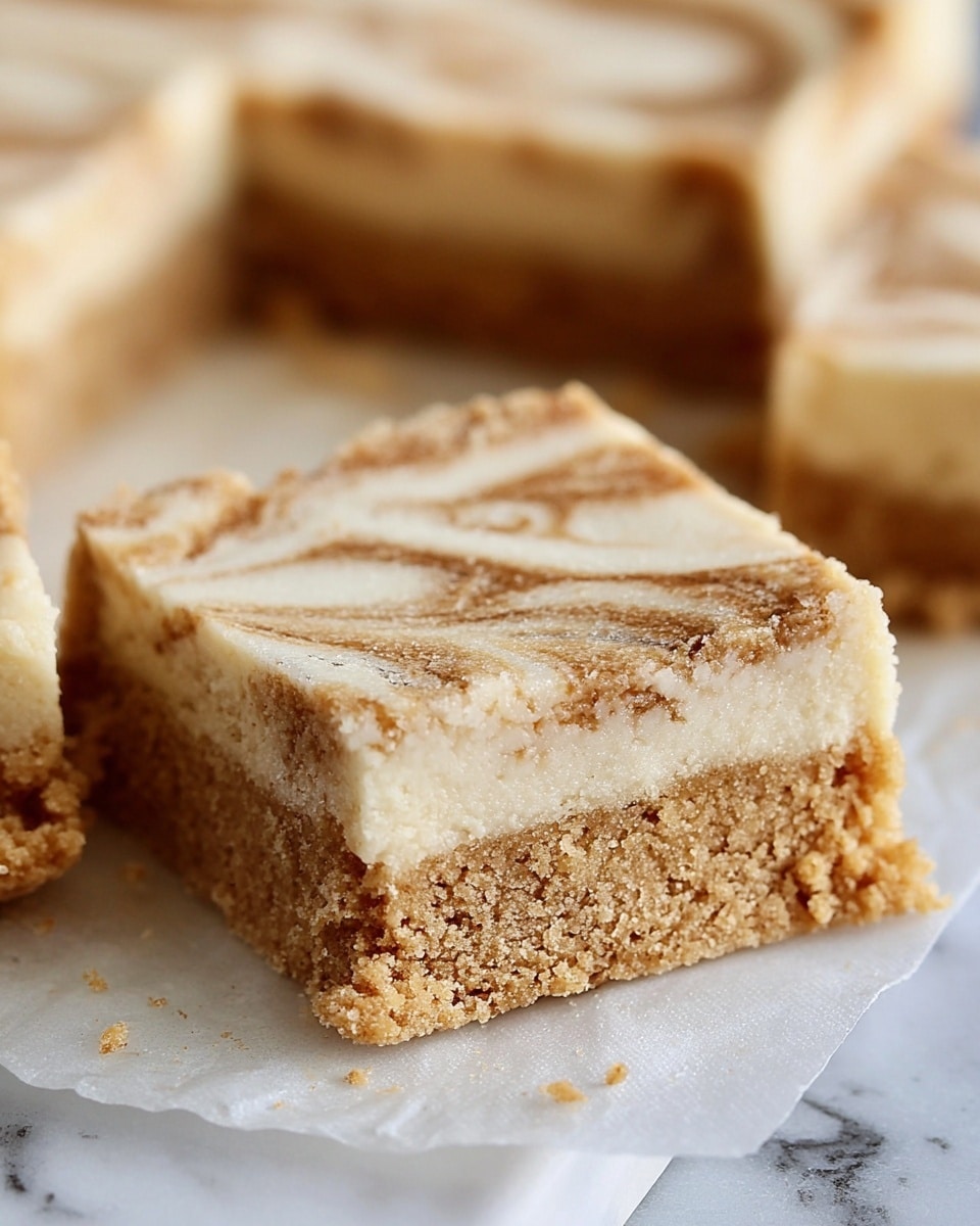 The image shows a close-up of a bar-shaped dessert with two distinct layers resting on parchment paper over a white marbled surface. The bottom layer is thick, light golden-brown, and slightly crumbly in texture. The top layer is thinner, creamy white with light brown swirls running through it, giving a marbled effect. The bar is cut into a square shape, and a few other pieces are visible in the blurred background. The texture appears soft but firm enough to hold its shape well. Photo taken with an iphone --ar 4:5 --v 7