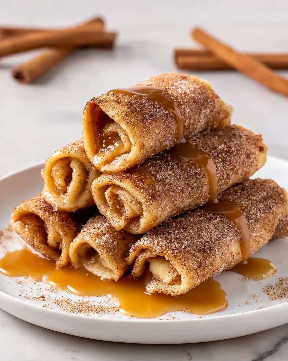 A white plate holds a stack of six rolled pastries arranged in two layers, with three rolls at the bottom and three on top. Each roll is dusted with a light brown cinnamon-sugar mixture, giving a grainy texture, and golden caramel sauce drizzles over the rolls, pooling slightly on the plate. The pastry appears lightly browned and crisp, with a soft, slightly visible filling inside. In the background, two cinnamon sticks lay on the white marbled surface, adding a warm, rustic touch. Photo taken with an iphone --ar 4:5 --v 7
