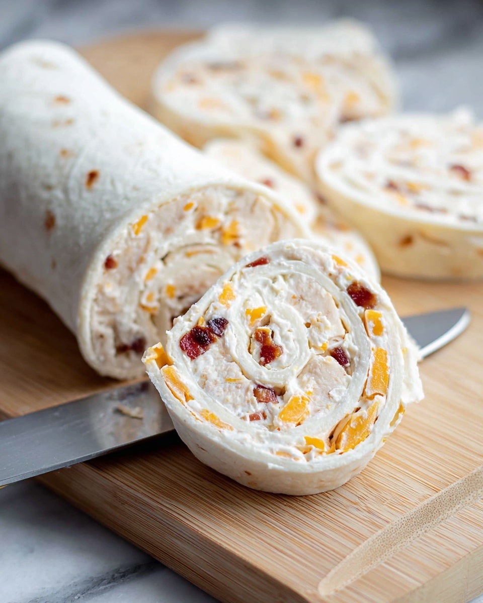 A white flour tortilla rolled tightly with a creamy filling that has two main layers: a smooth white cream cheese base with small pieces of cooked chicken mixed in, and orange shredded cheddar cheese scattered throughout, along with small bits of dark red bacon or similar meat inside. The roll is sliced into round pinwheel shapes, revealing circular layers of the tortilla and filling in a spiral. The pieces are placed on a light wooden cutting board with a close-up view of a silver knife cutting one piece. The background is a white marbled texture. photo taken with an iphone --ar 4:5 --v 7