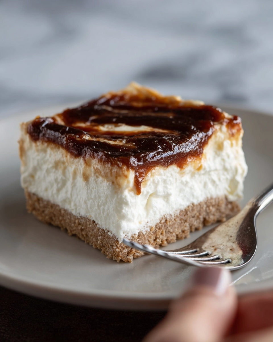 A close-up of a square dessert piece with three clear layers, placed on a white plate. The bottom layer is a dense, crumbly light brown crust with visible small grains. The middle layer is thick, fluffy, and white, resembling whipped cream or a mousse with a soft texture. The top layer has a glossy, caramelized dark brown spread unevenly covering the white layer, showing some smooth runs and patches. A metal fork is placed on the right side of the plate, and a woman's hand is gently holding the edge of the plate; the background is a white marbled texture. Photo taken with an iphone --ar 4:5 --v 7