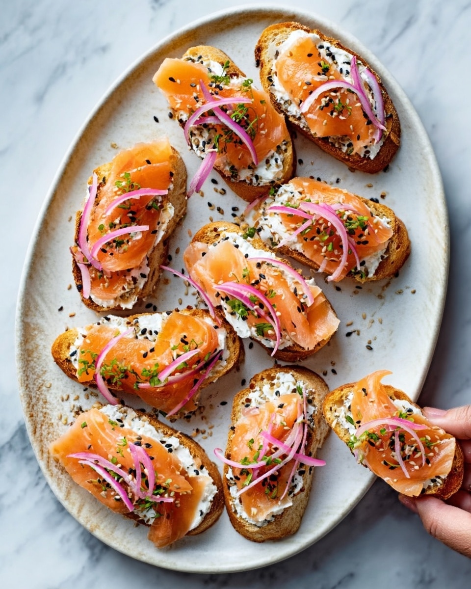 The image shows a white oval plate on a white marbled surface, filled with eight pieces of toasted bread topped with several layers. Each toast has a base of creamy white spread, followed by thin slices of pink-orange smoked salmon. On top of the salmon, there are thin light purple onion slices, finely chopped green herbs, and small black and white sesame seeds scattered over everything. A woman's hand is reaching to pick up one of the toasts. photo taken with an iphone --ar 4:5 --v 7